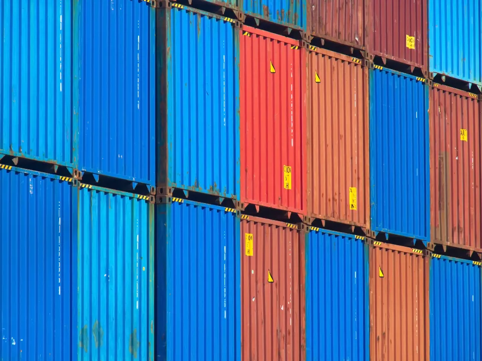 Stacked blue and orange shipping containers at a port